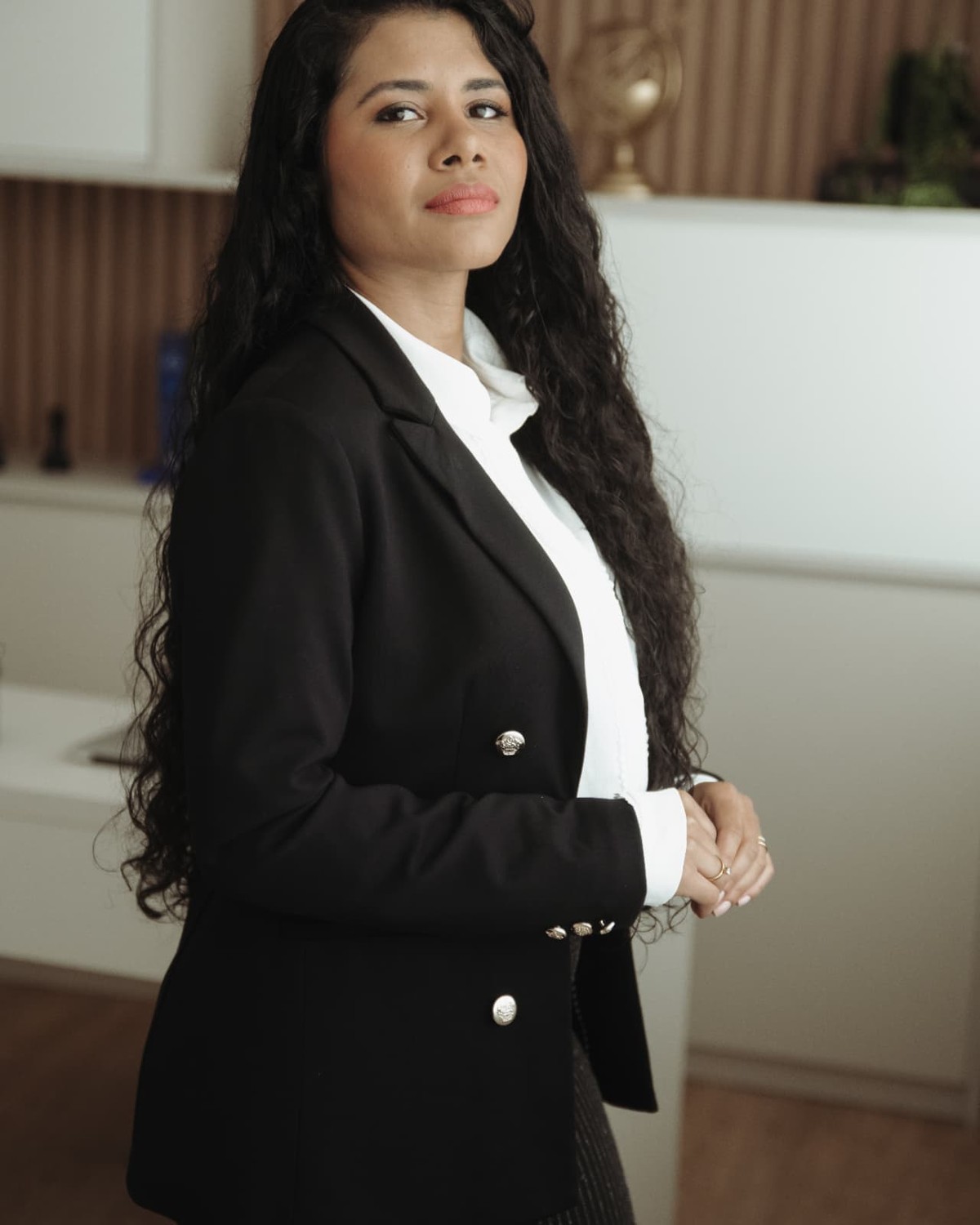 Ingrid Alegri, Gestora Financeira, com blazer preto em ambiente corporativo